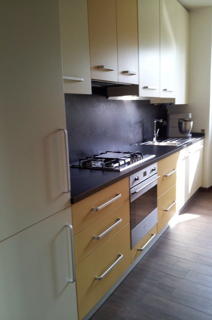 Cucina lineare bianca e gialla con piano scuro