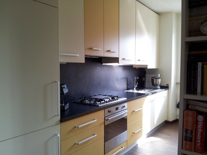 Cucina lineare bianca e gialla con piano scuro